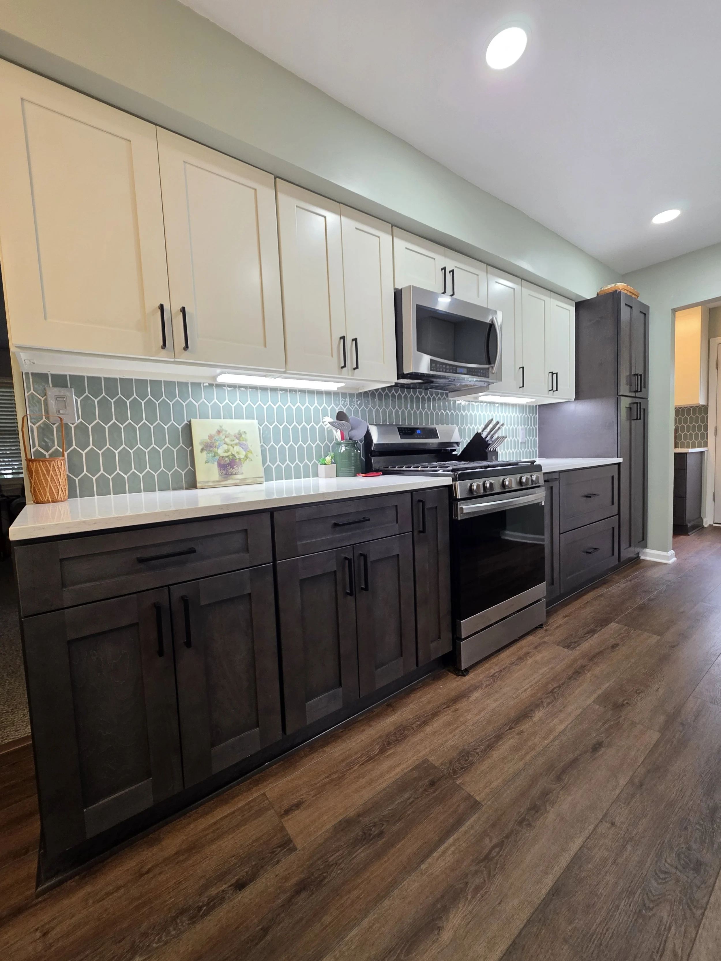 Tim and Mary’s remodeled kitchen with light upper cabinets, dark lower cabinets and a patterned backsplash.