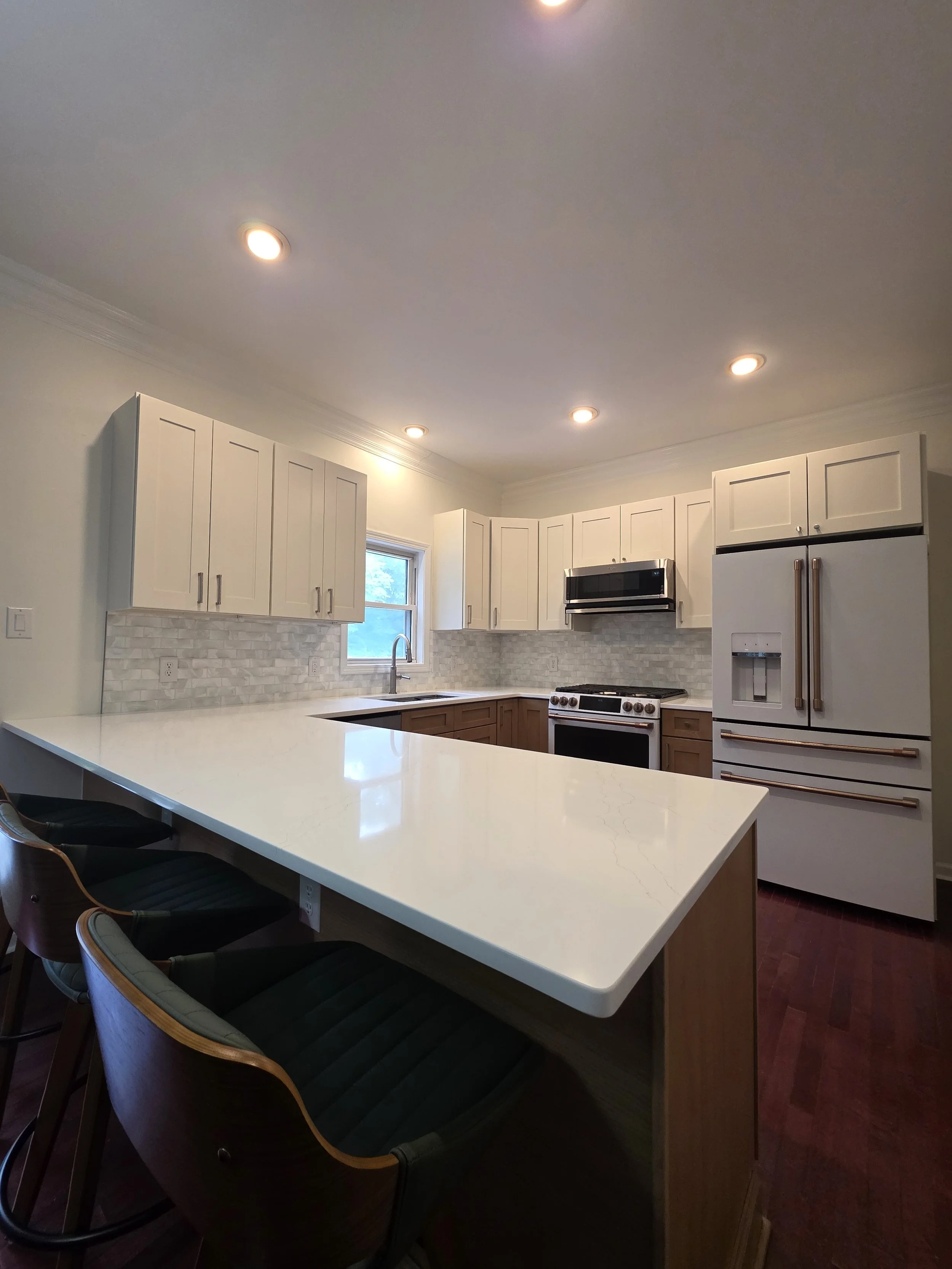 Finished kitchen peninsula with a light countertop, dark seating, and two-tone cabinetry.
