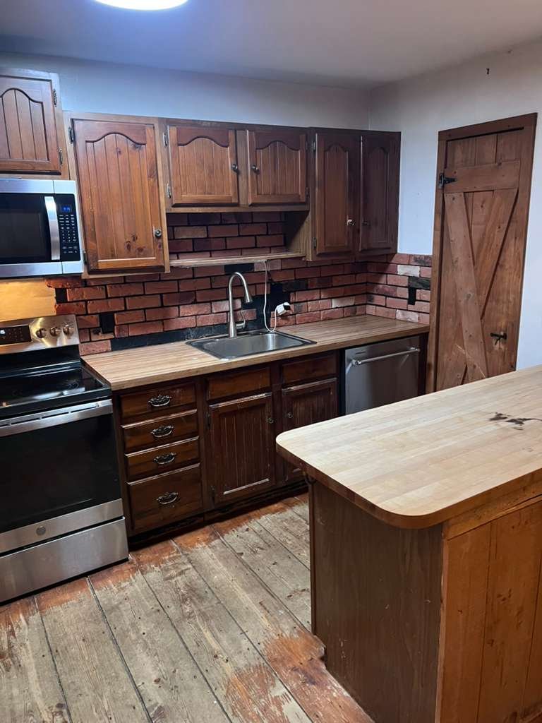 Before renovation: the original wood cabinetry, tile backsplash and older kitchen flooring.