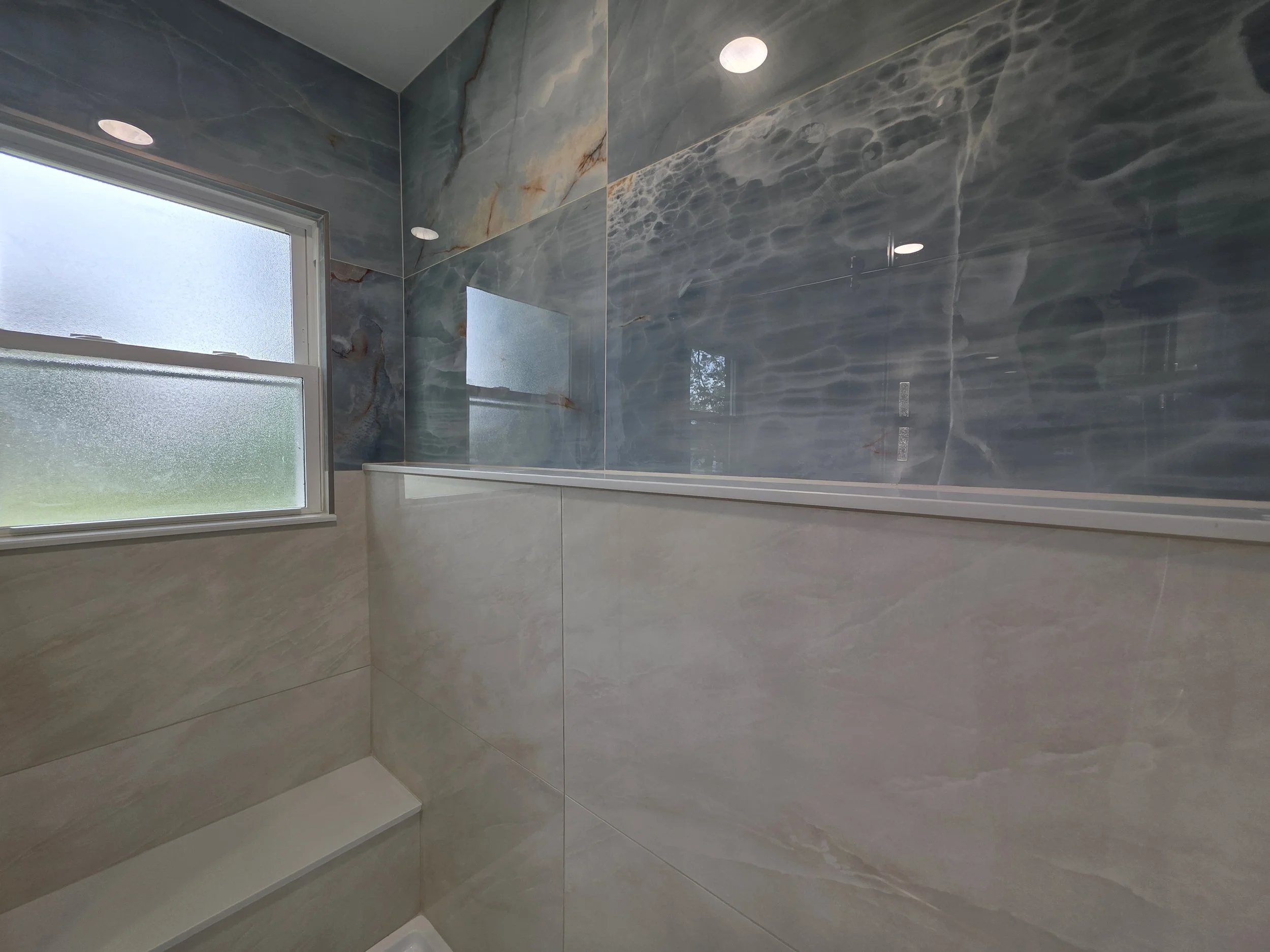 Shower window and contrasting blue and beige wall tile.