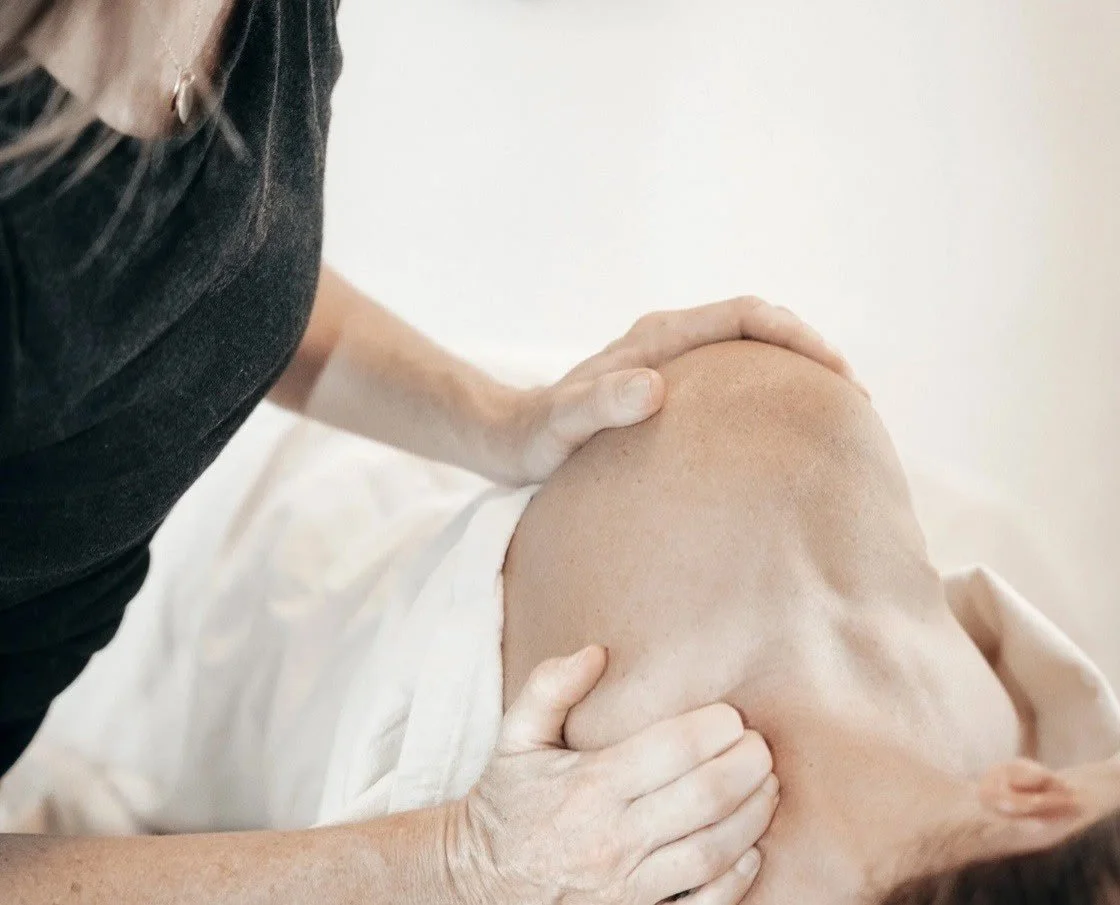 A person receiving a massage on their shoulder from a massage therapist.