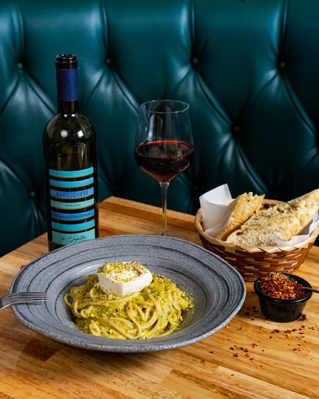 A cozy corner booth with pistachiosa, garlic bread, and a bottle of sangiovese? That is paradiso.