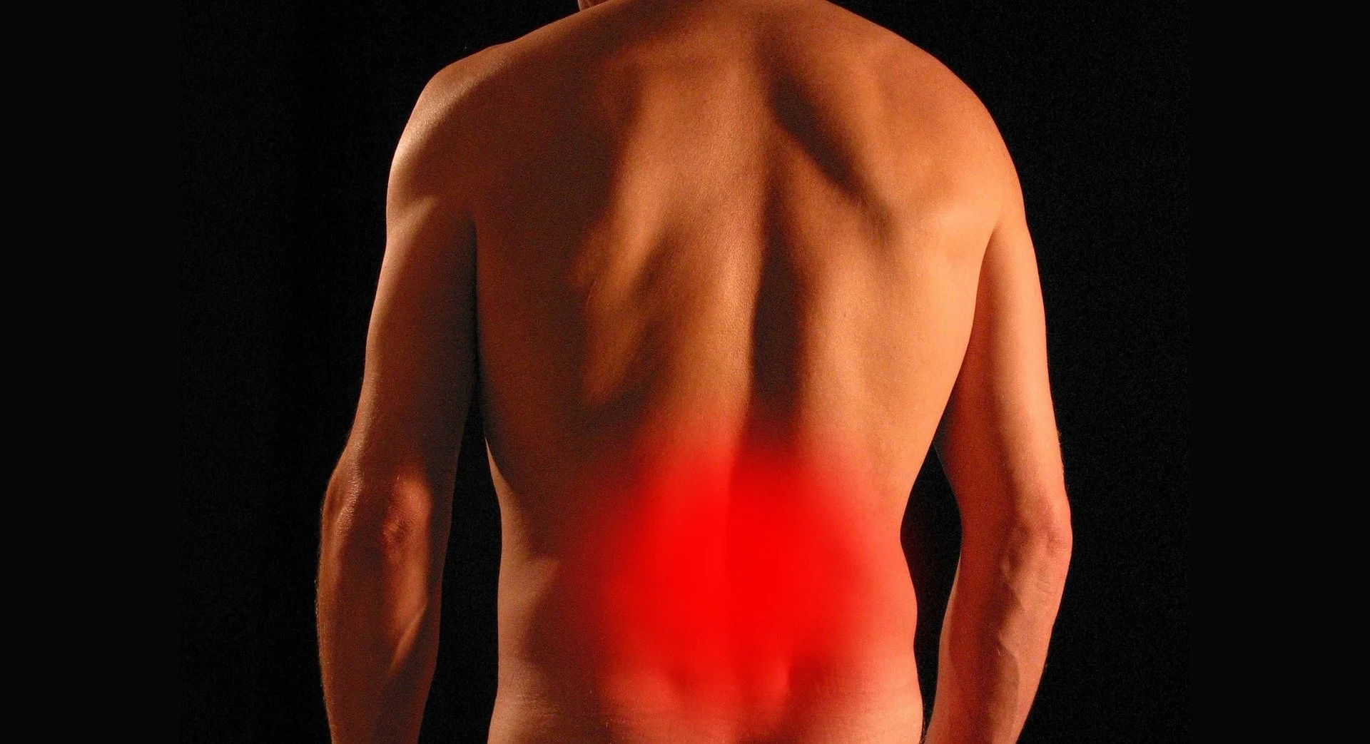 Back of a shirtless person with a red highlight on their lower back.