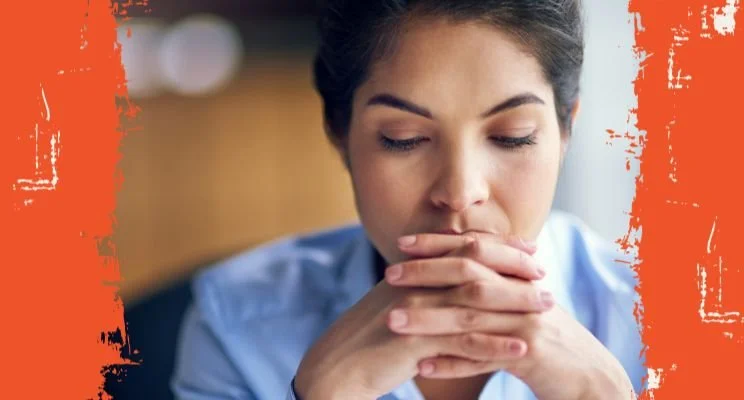 ADHD-ish blog, Woman in blue shirt with hands clasped, eyes closed, Why "I Work Better Under Pressure" Backfires for ADHD Business Owners, adhd mindset and motivation podcast, adhd entrepreneur chronic stress, high-functioning adhd