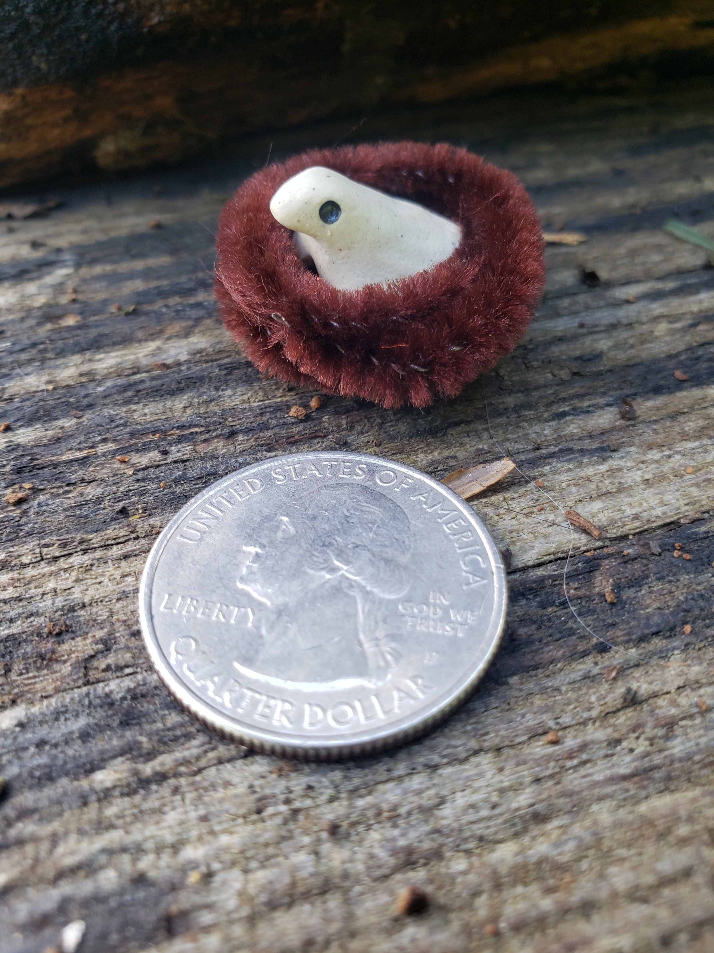 whimsical clay bird sits in a pipe cleaner nest