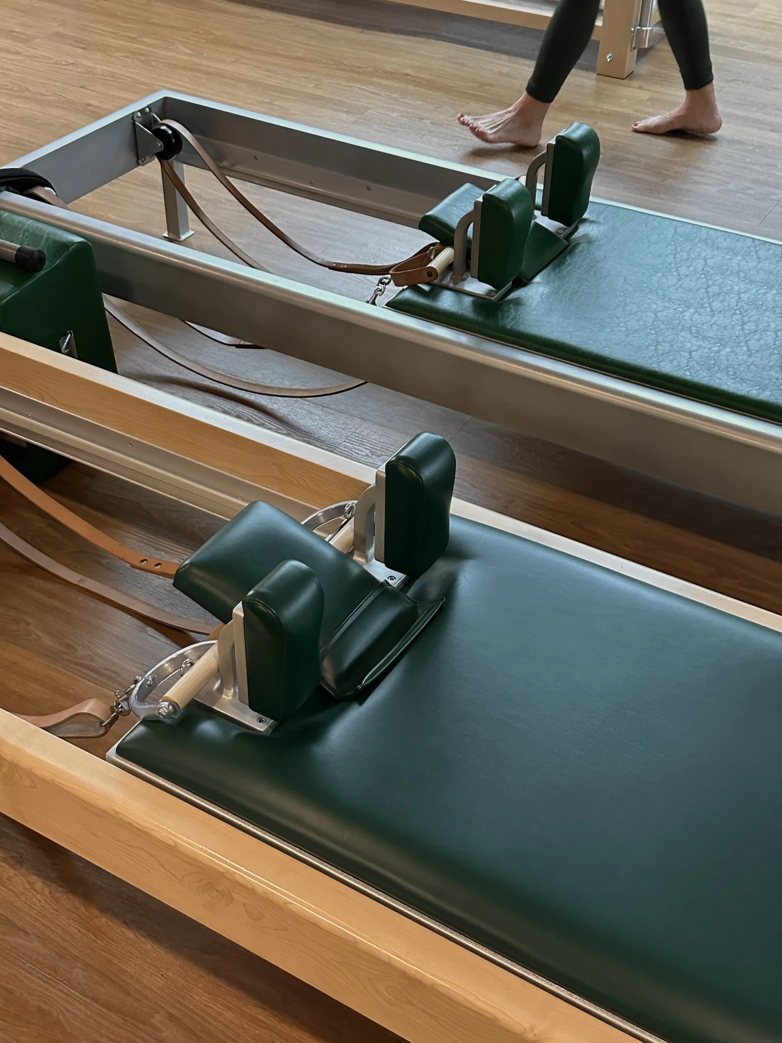 Pilates reformer machine with green upholstery in a gym setting