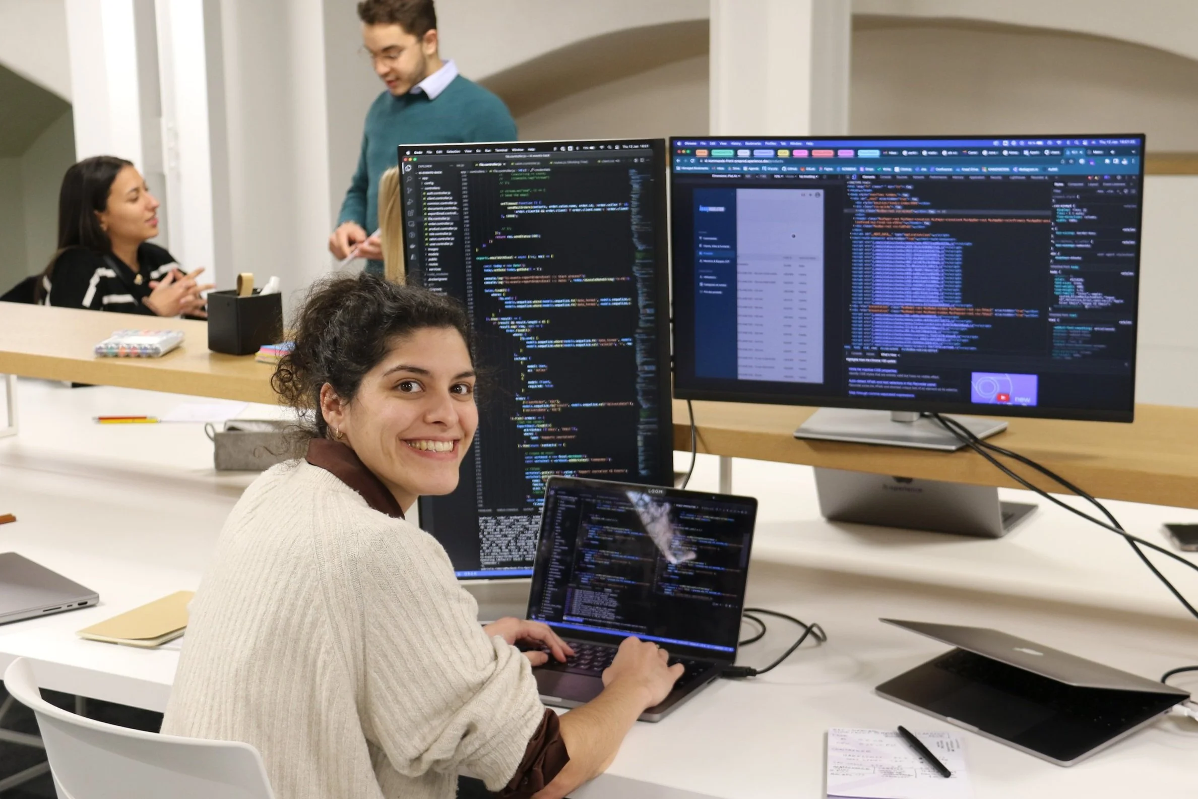 L'équipe discute et sourit devant des écrans de code