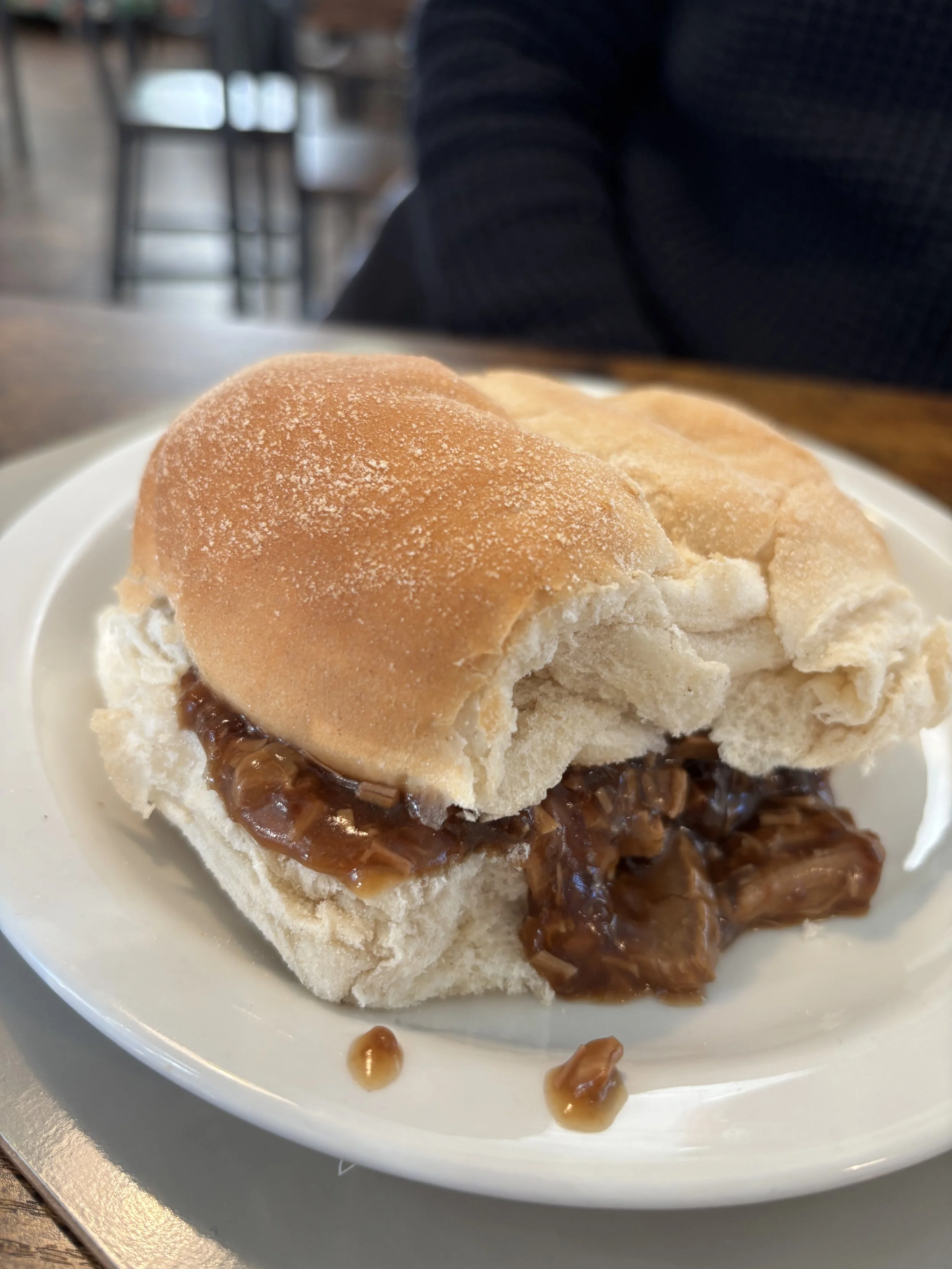 A plate with a bread roll filled with caramelized filling in a restaurant setting.