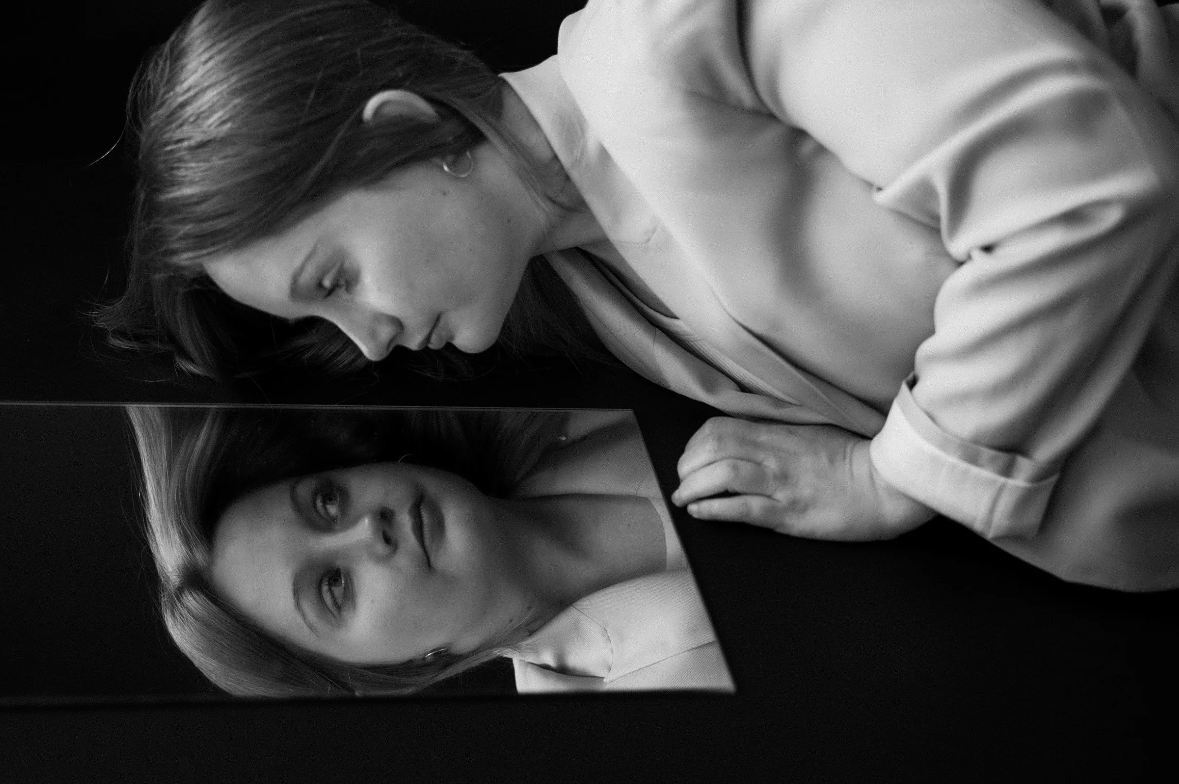 A black and white photo of two women looking at something on a screen, with one woman leaning over and closely observing while the other looks on.