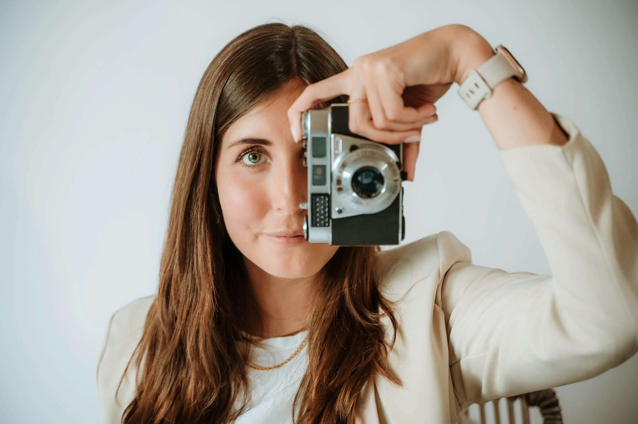 Woman with brown hair taking a photo with a vintage camera.