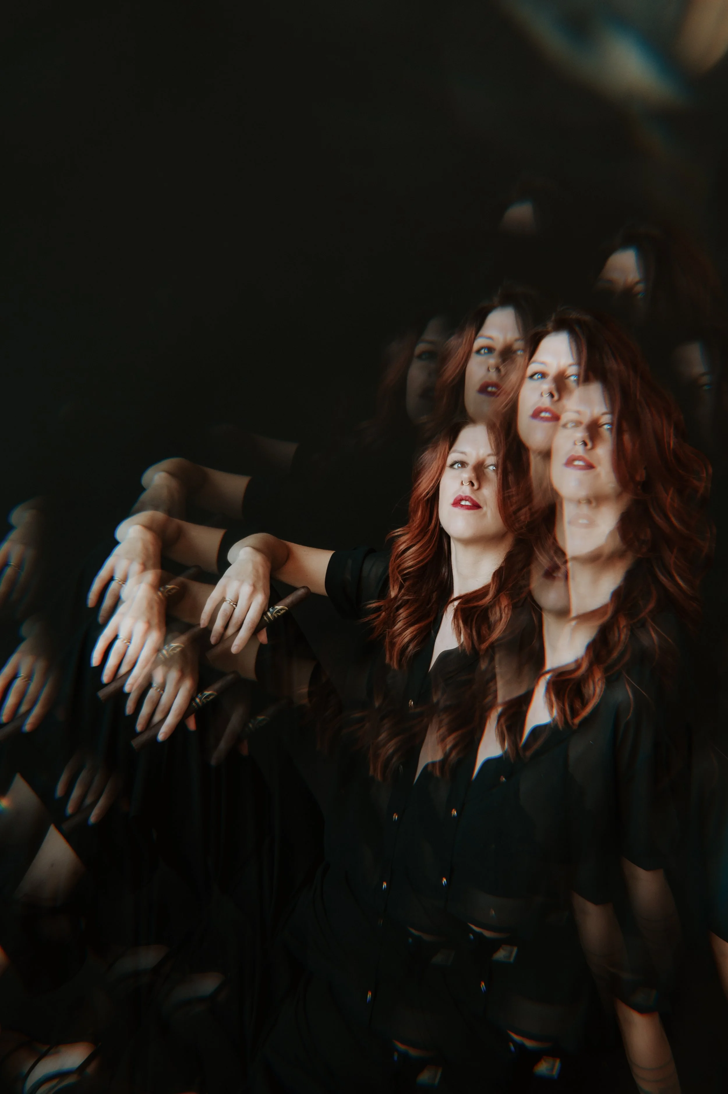 Multiple overlapping images of a woman with long reddish-brown hair, wearing a black top, and a septum piercing, with her eyes open and looking in various directions.