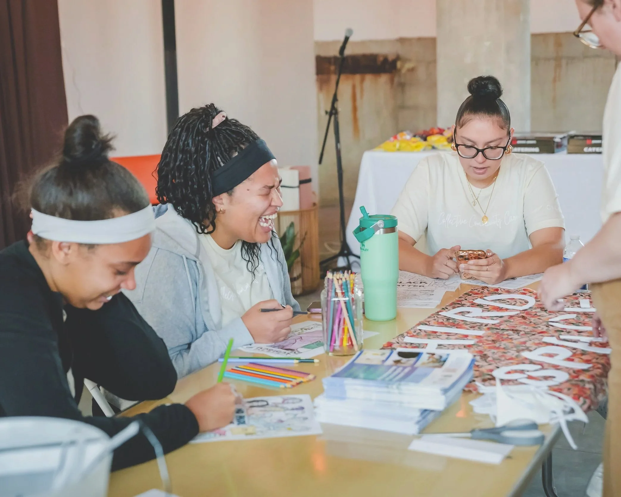 Three Black women coloring together and smiling.