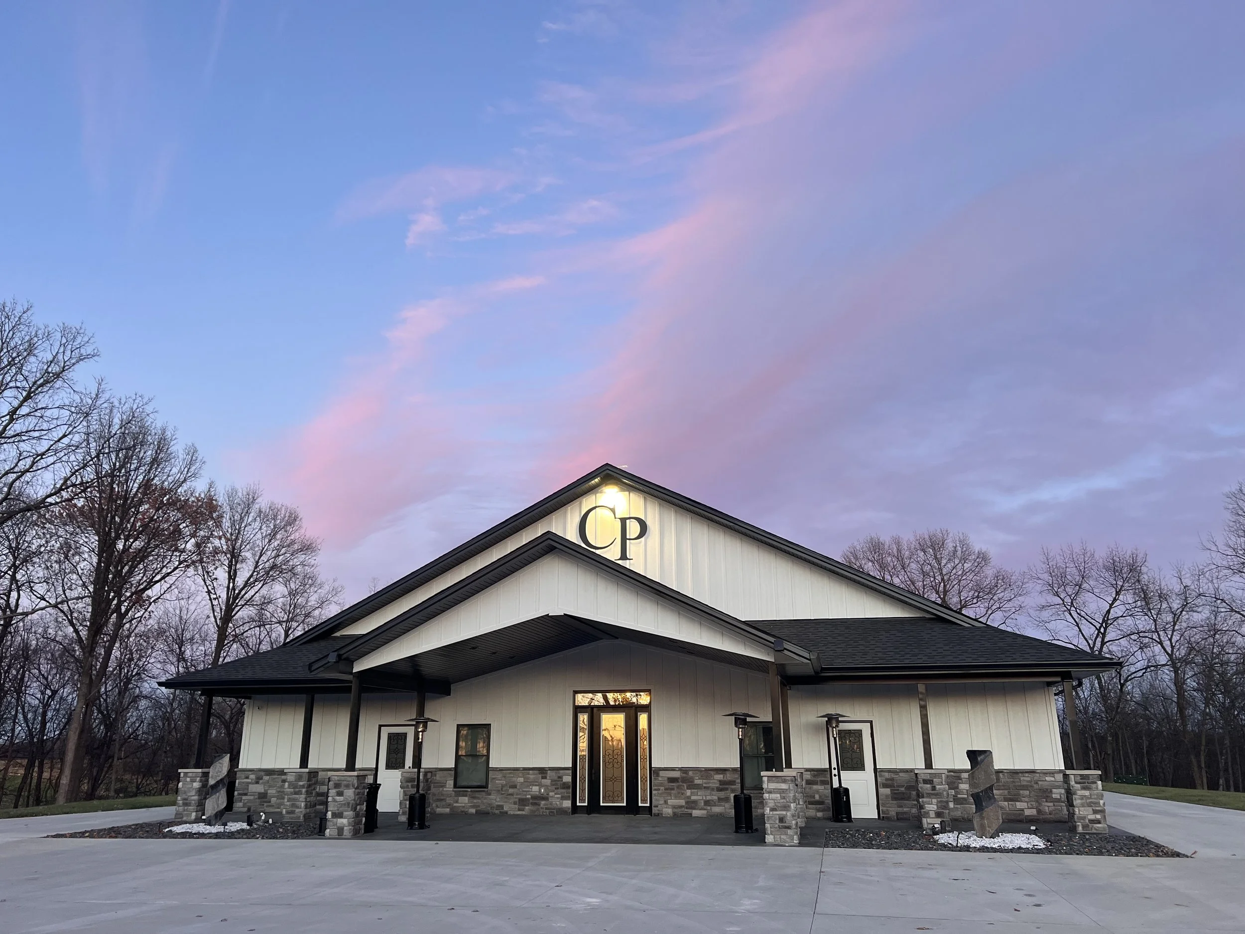 Building with "CP" on facade at sunset, surrounded by leafless trees.