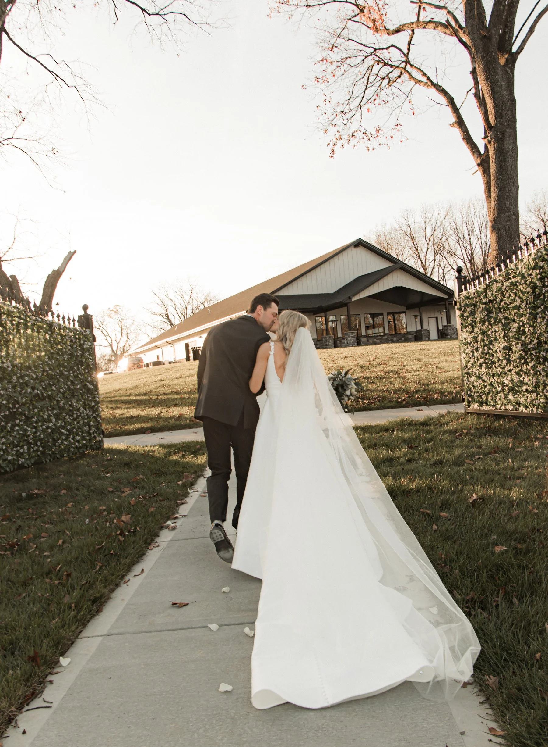 Bride and groom walking on pathway, outdoor wedding venue, sunset