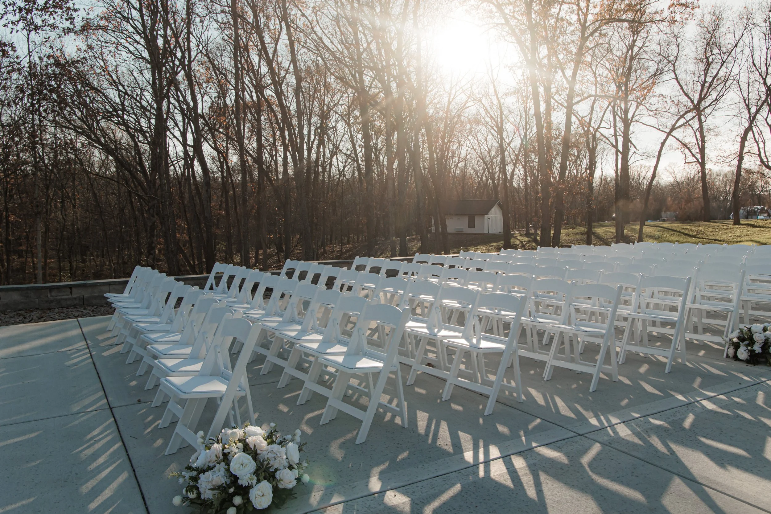 Outdoor wedding venue with white chairs and floral arrangements