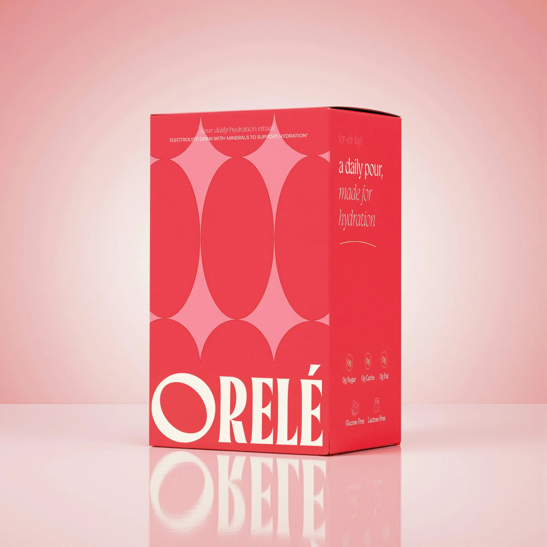 Pink box with white text and graphics promoting a sugary snack, including nutritional info indicating it's sugar-free and lactose-free, with a reflection on a pink surface.