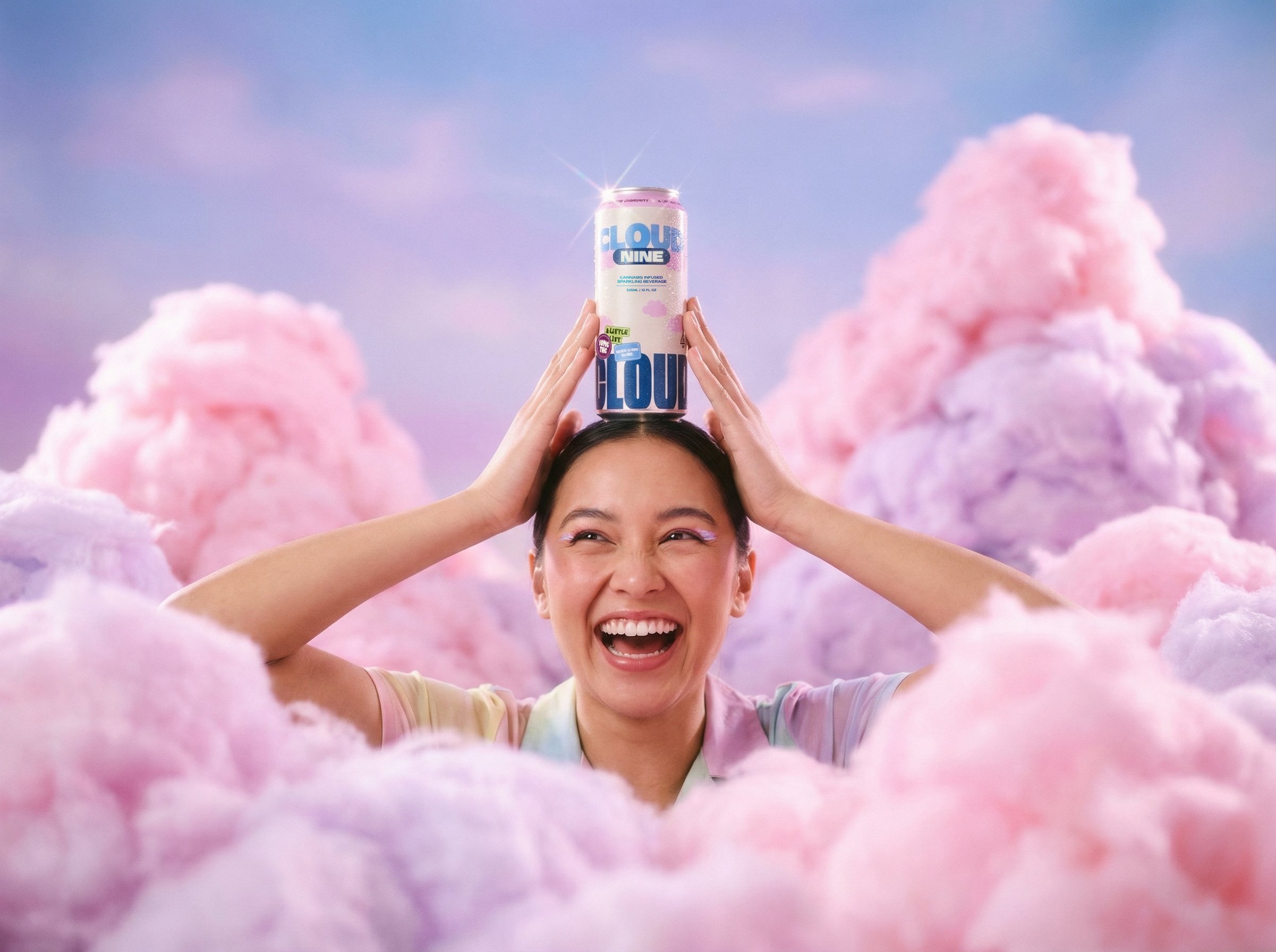 A person with short dark hair holding a can of Cloud Nine sparkling beverage above their head. The person is smiling and appears joyful, surrounded by pink and purple cotton candy clouds and a pastel sky background.