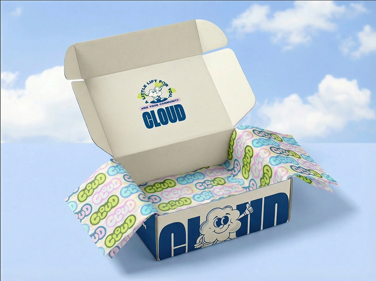 Open box with cloud mascot and branded tissue paper featuring clouds and the word 'CLOUD' on the tissue, in front of a blue sky background.
