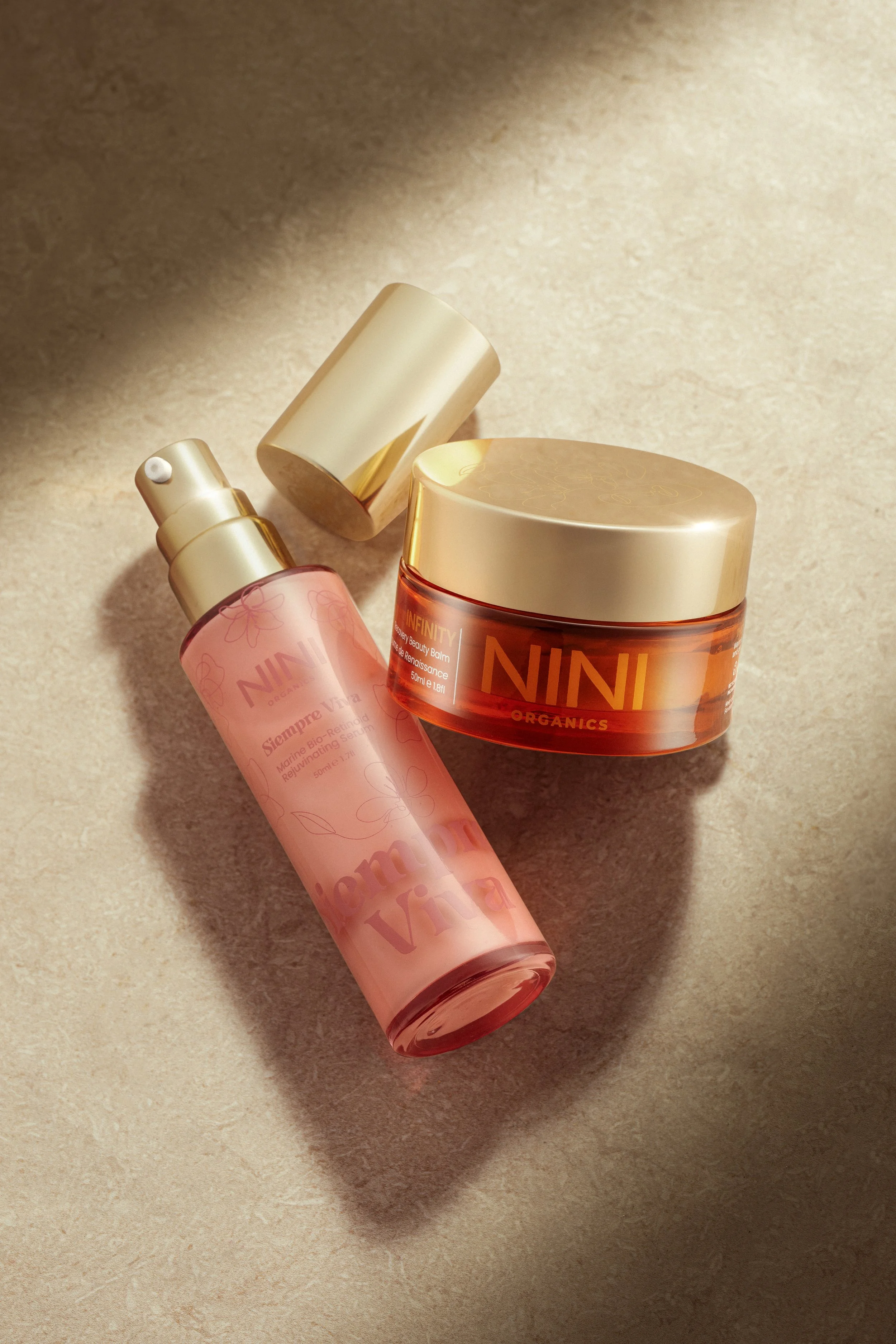 A collection of skincare products, including a pink spray bottle and an orange container, on a beige surface.