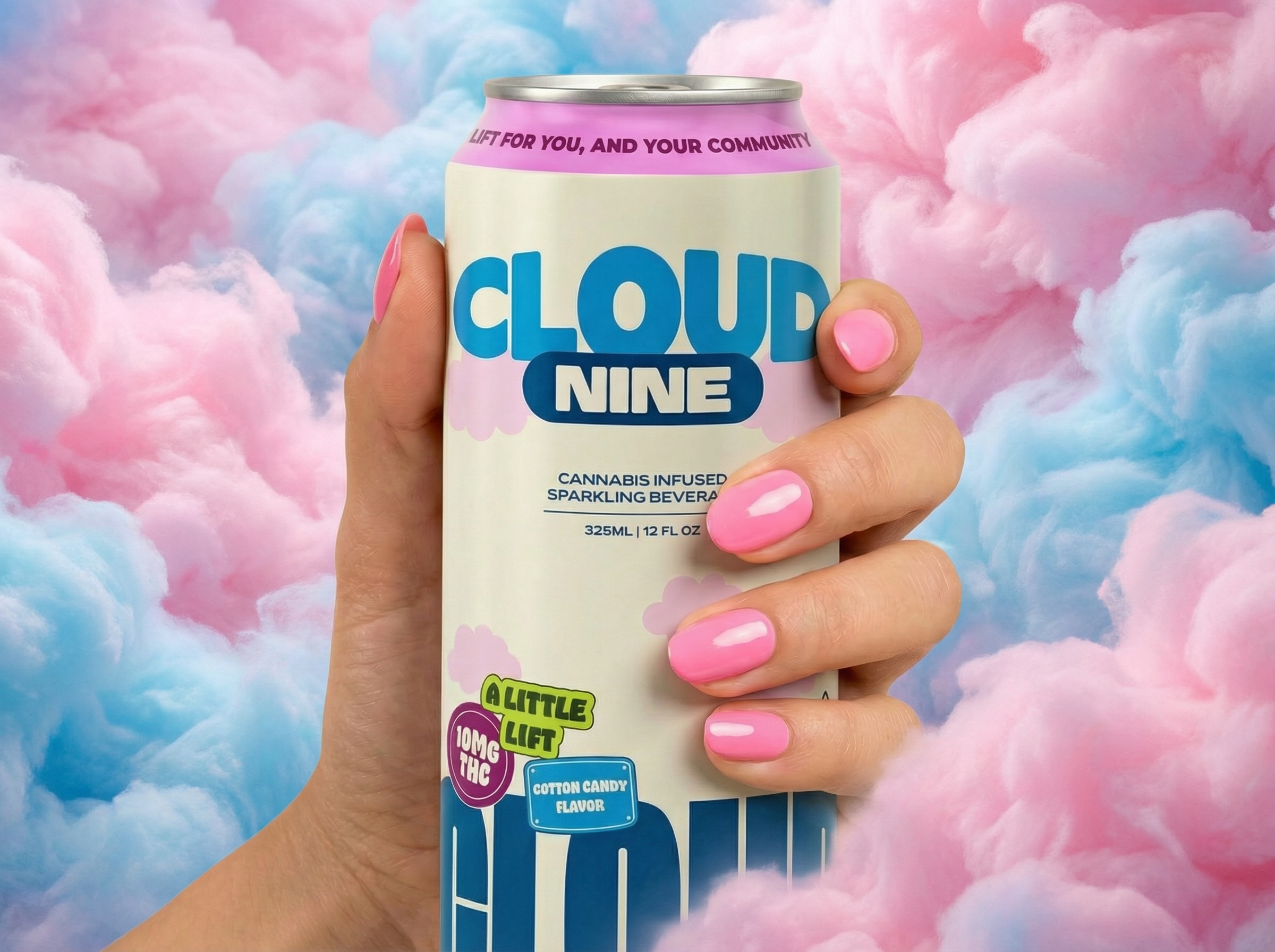 Hand with pink-painted nails holding a can of Cloud Nine cannabis-infused sparkling beverage against a background of pink and blue clouds.