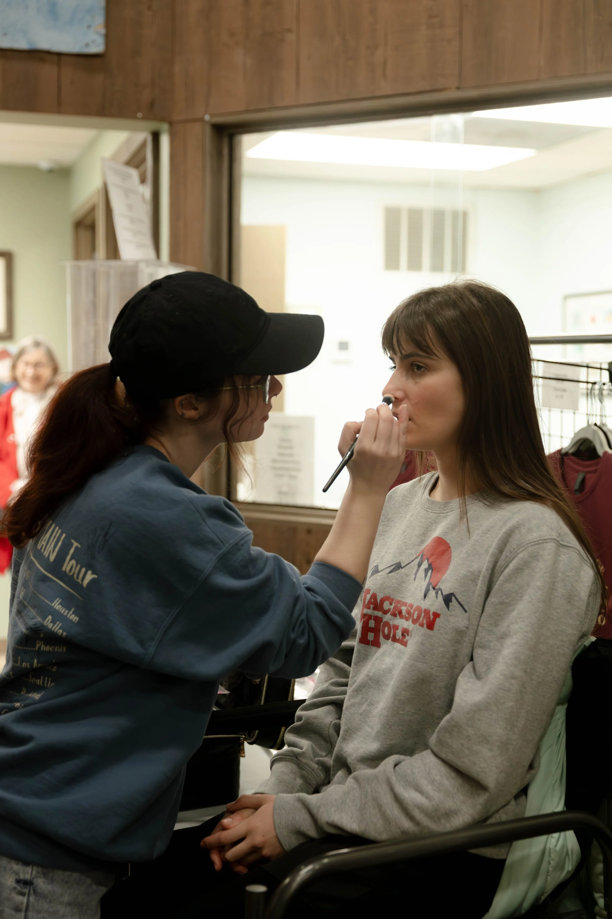 A makeup artist applies makeup to a woman sitting in a technique.