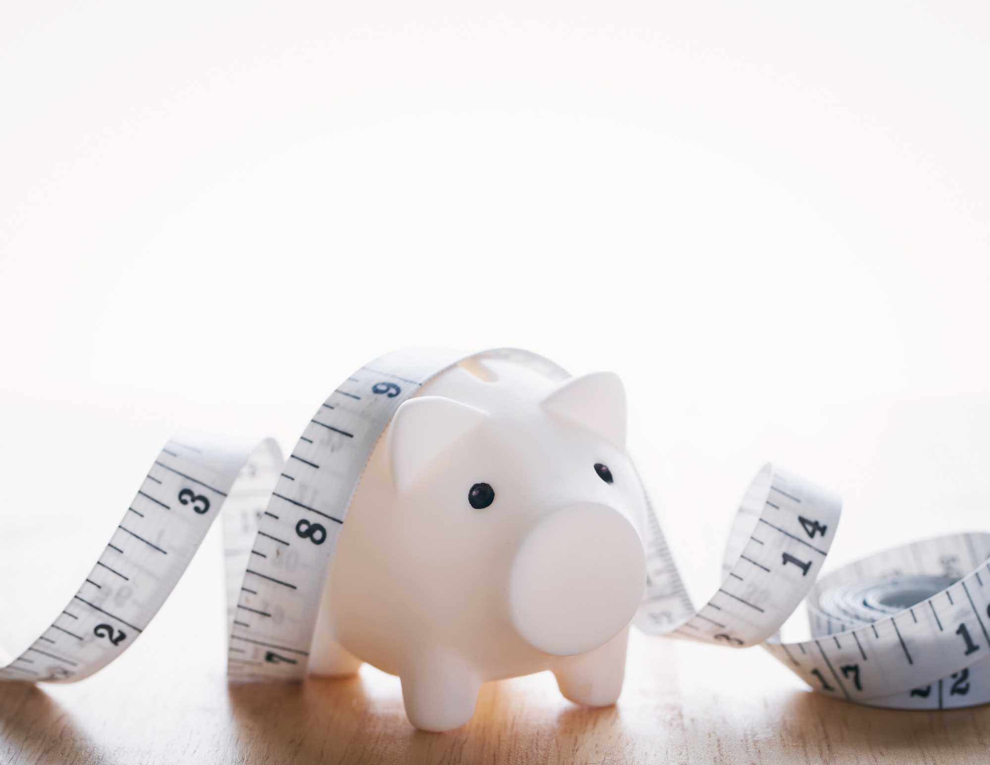 an image of a light coloured piggy bank with a measuring tape on it