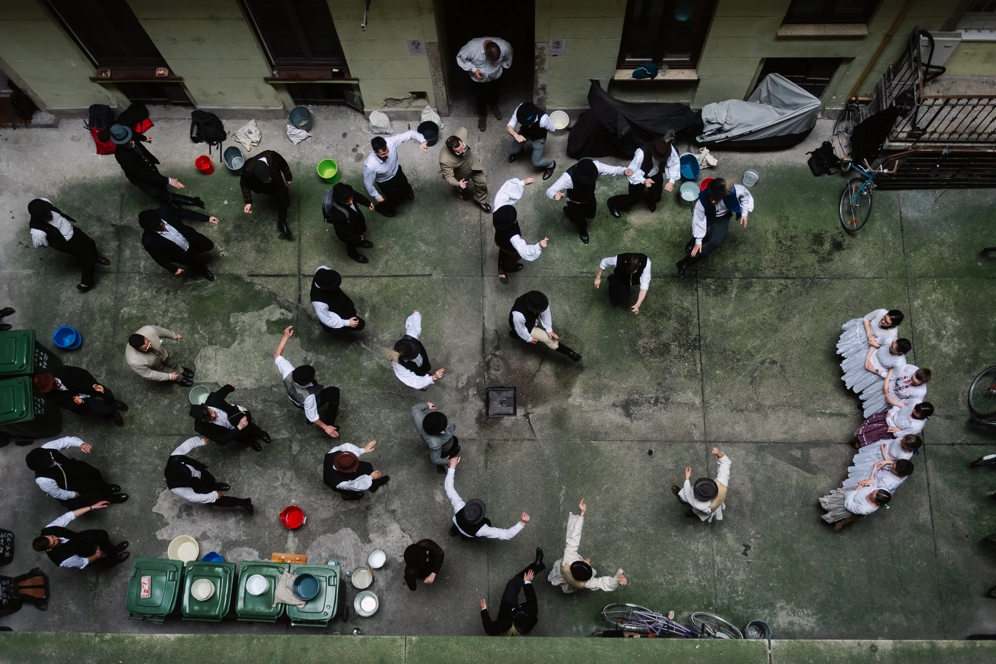 The boys are dancing in the courtyard of a classical tenement building on the boulevard. The girls are prepared for the sprinkling, the buckets are full.