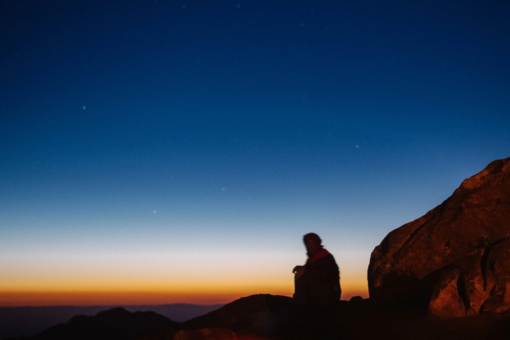 Dawn. A man is waiting for the sunrise on the summit.