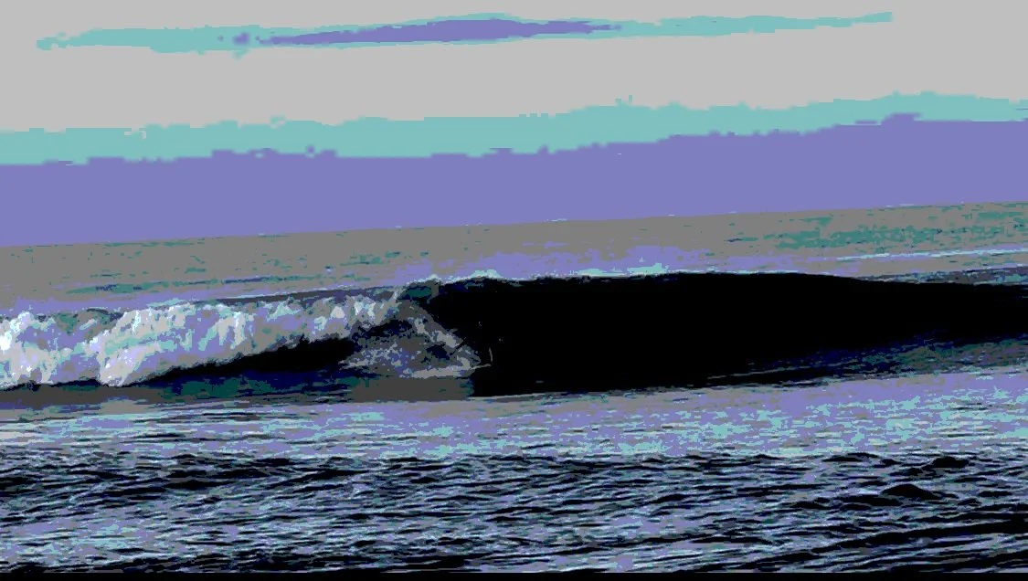 Ocean wave breaking with a colorful, stylized sky in the background.