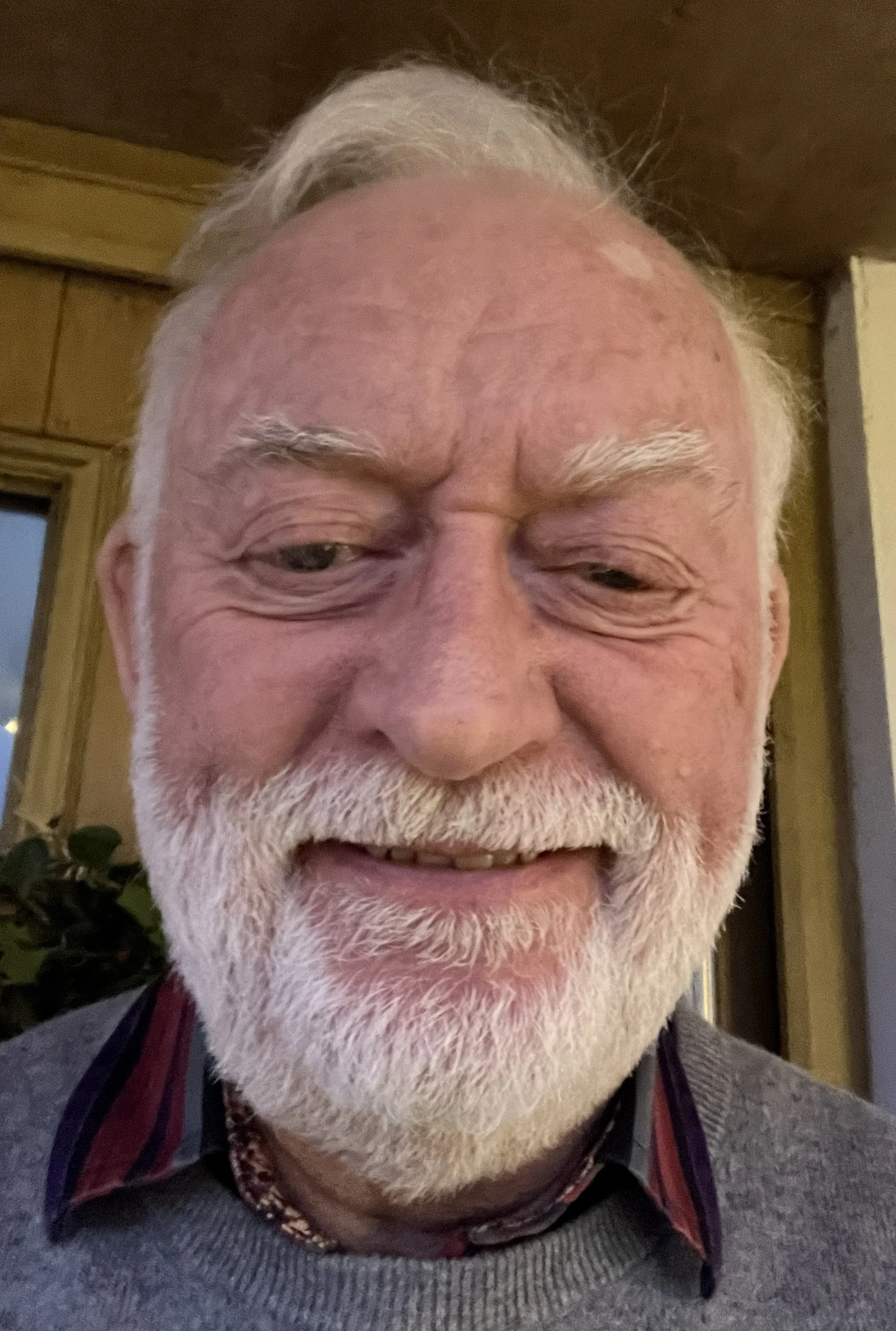 A rugged mountainous landscape with snow patches, a glacier, and earthy-colored rocks amid steam rising from geothermal activity.