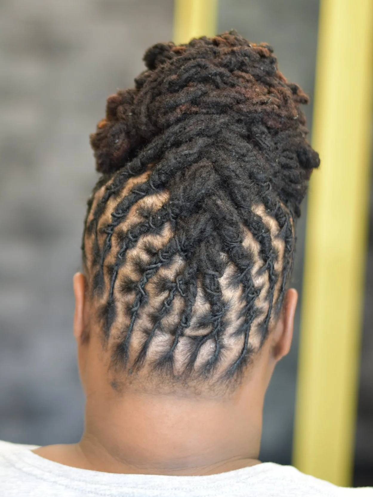 Creative loc updo with barrel twists and a clean side shave, showcasing intricate loc styling for woman.