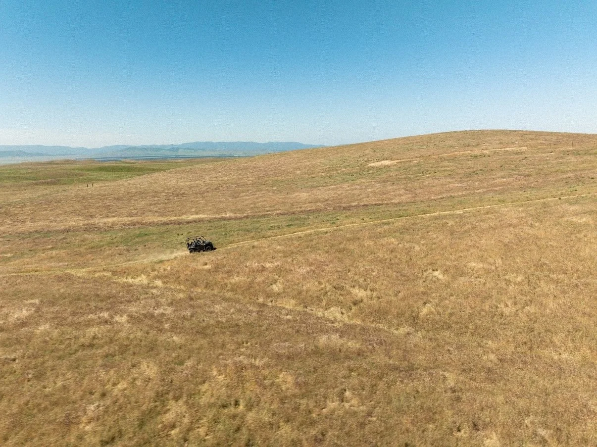 A lone UTV moves across vast open grasslands at Carissa Plains Outfitters, highlighting the scale and quiet of Central California hunting terrain