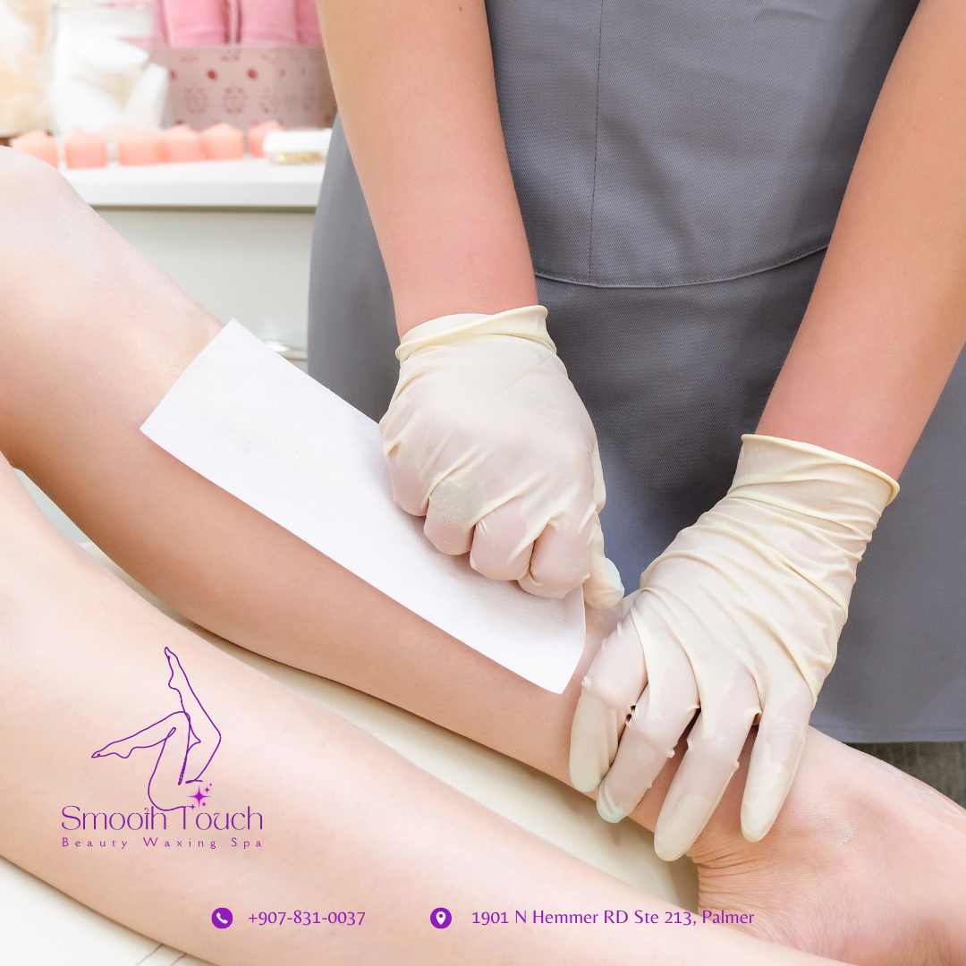 A person wearing gloves is waxing a person's leg at a beauty spa, with wax strips applied on the leg, while another person applies wax or pulls hair from the leg.