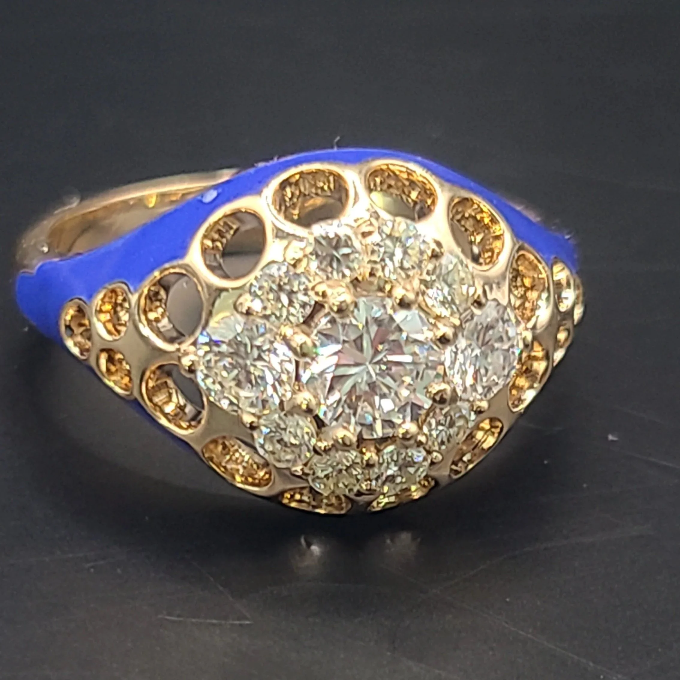 Custom-designed blue enamel ring set in yellow gold with center diamond and diamond halo. Open cutouts in the gold 