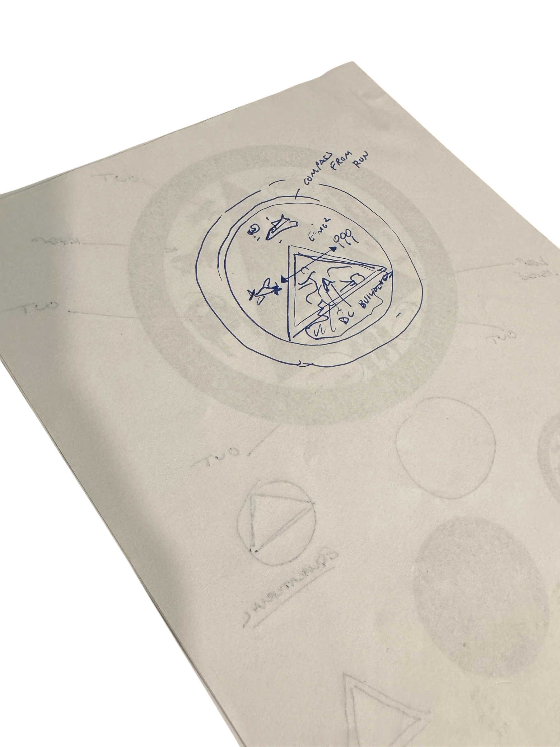 Hand-drawn diagram of an emblem with annotations and surrounding concentric circles, sketching a conceptual plan.