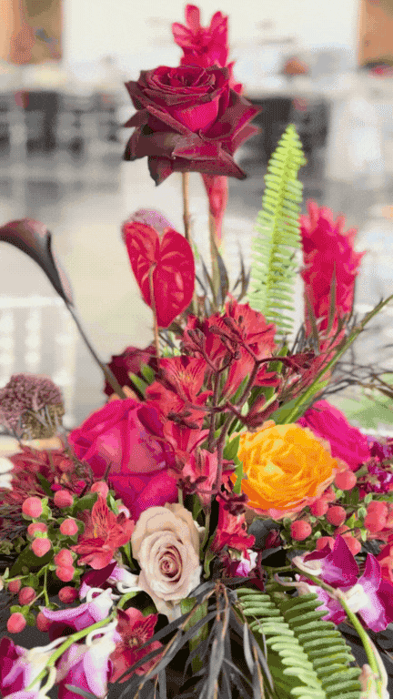 Colorful bouquet of pink, red, yellow, and white flowers with green ferns and leaves