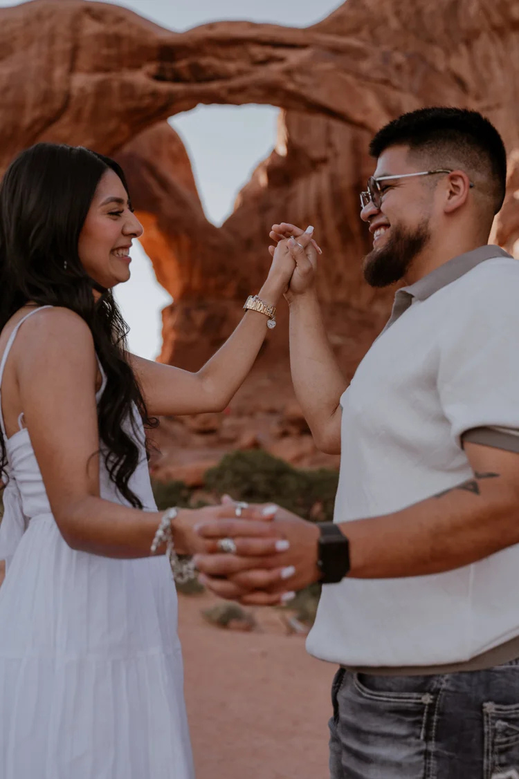 Couple holding hands during elopement ceremony at Arches National Park Moab Utah