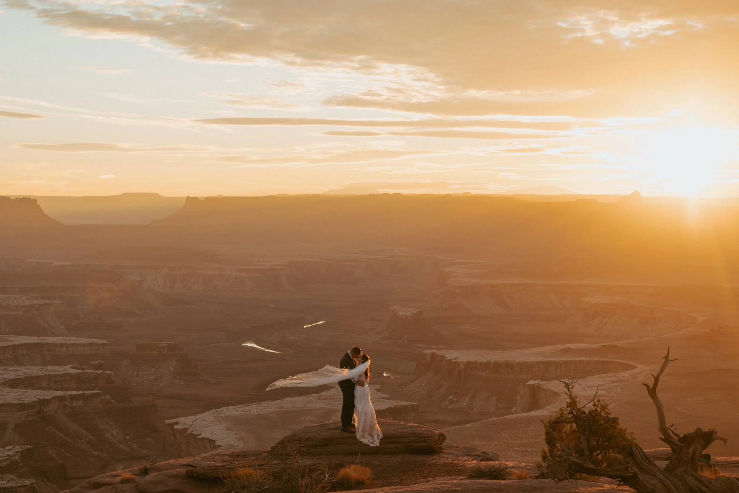 Newlyweds sharing first kiss at sunset during Utah desert wedding ceremony