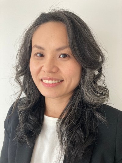 A woman with long, wavy gray hair smiling at the camera against a plain white background.