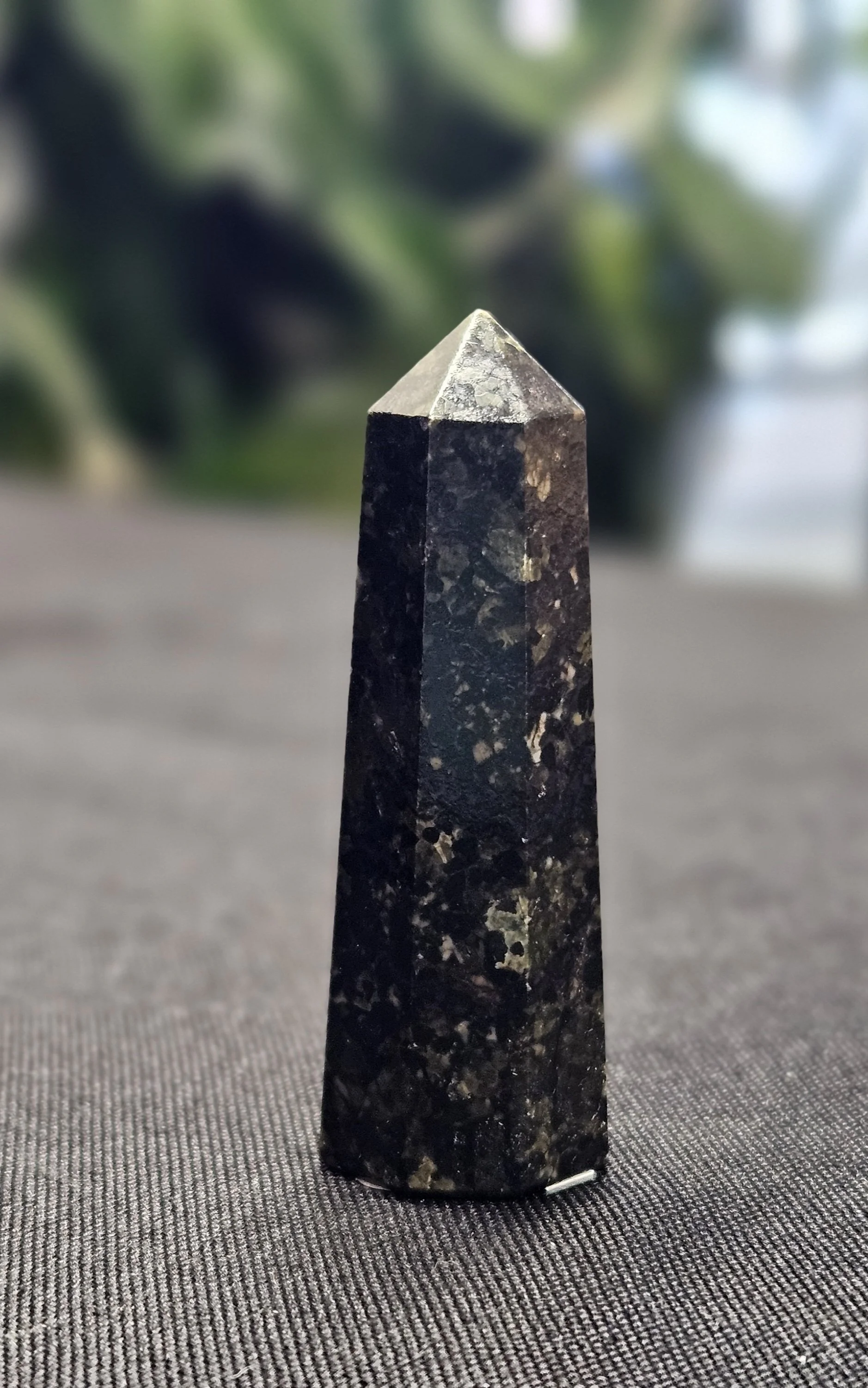 Dark Nuummite stone with subtle gold and blue iridescent flashes in polished form.