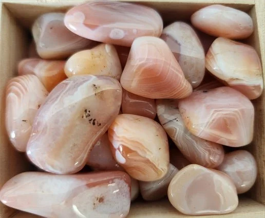 Apricot Agate stone with soft peach and warm orange tones, showing a smooth, polished surface and gentle natural banding.