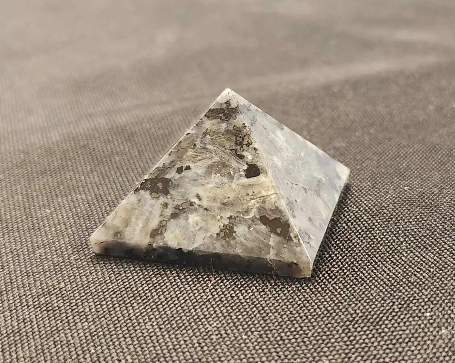 Dark grey larvikite stone with subtle silver-blue flash and polished surface showing feldspar patterning.