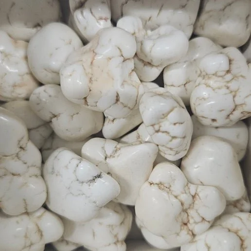 White Magnesite tumbled and rough stones with natural grey veining displayed on a neutral background.