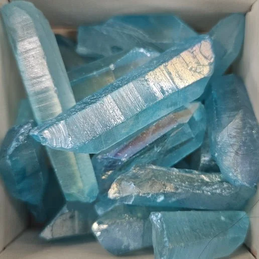 Aqua Aura Quartz crystal point with vibrant blue iridescent sheen, showing a smooth, reflective surface and luminous colouring.