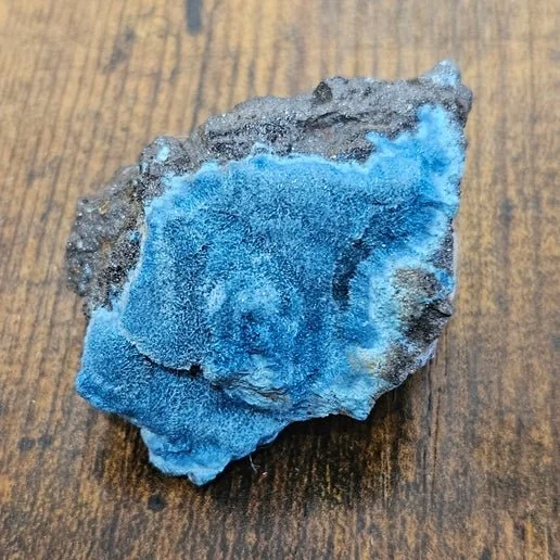 Deep blue Shattuckite stone with natural swirling patterns, shown polished and in rough mineral form.