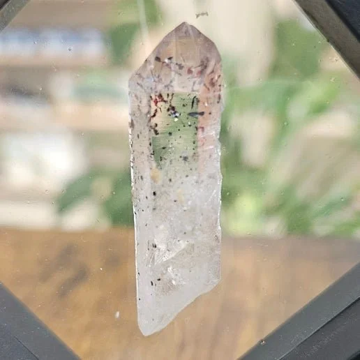 Harlequin quartz crystal with red hematite inclusions scattered through clear quartz