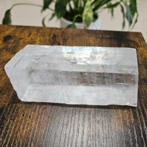 A clear Optical Calcite crystal, also known as Iceland Spar, with transparent, faceted surfaces and high clarity.