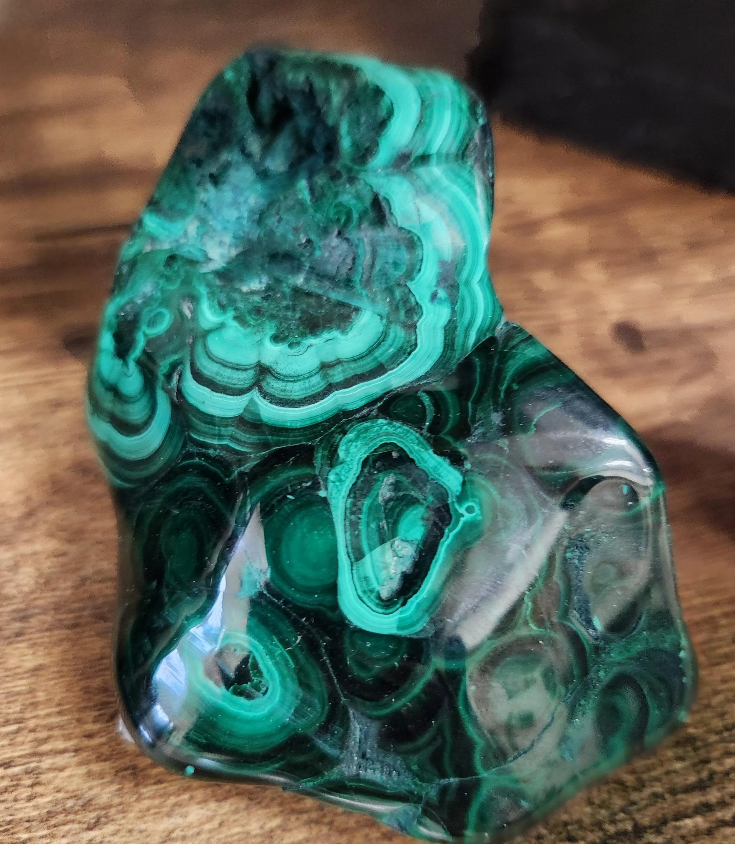 Polished and raw Malachite stones showing deep green colour with natural banded patterns and swirling formations.