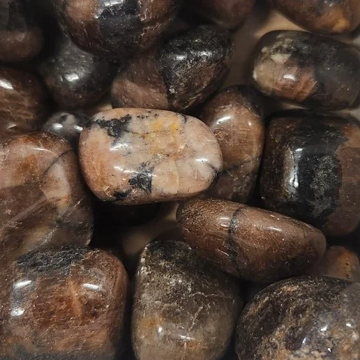 Chiastolite stone showing a natural dark cross pattern within a brown to grey matrix, symbolising balance and protection.