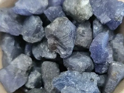 Deep blue and violet Tanzanite gemstones including raw crystals and faceted stones from Tanzania.